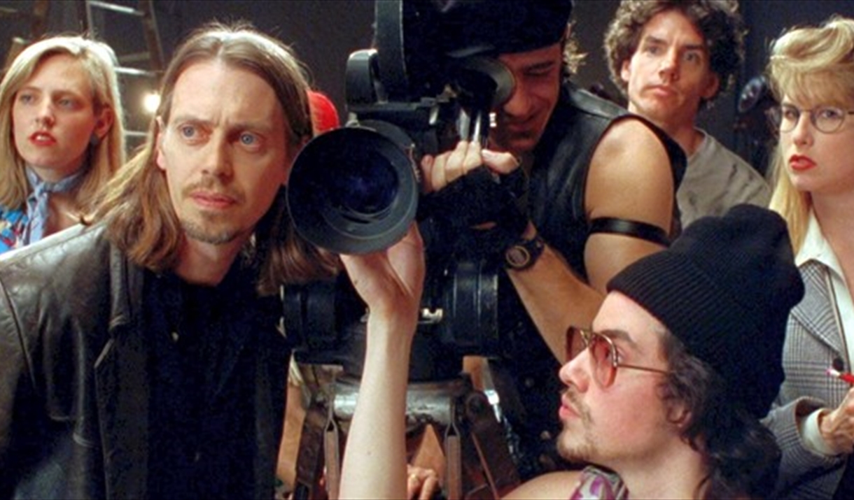 Still from the film "Living in Oblivion". showing the actors huddled around a camera.