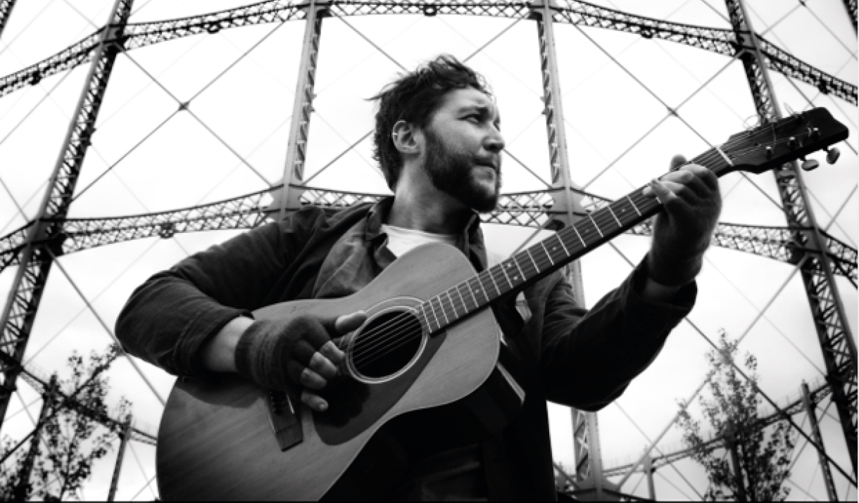 Man with guitar performing Firebird: an hour of folk tales.