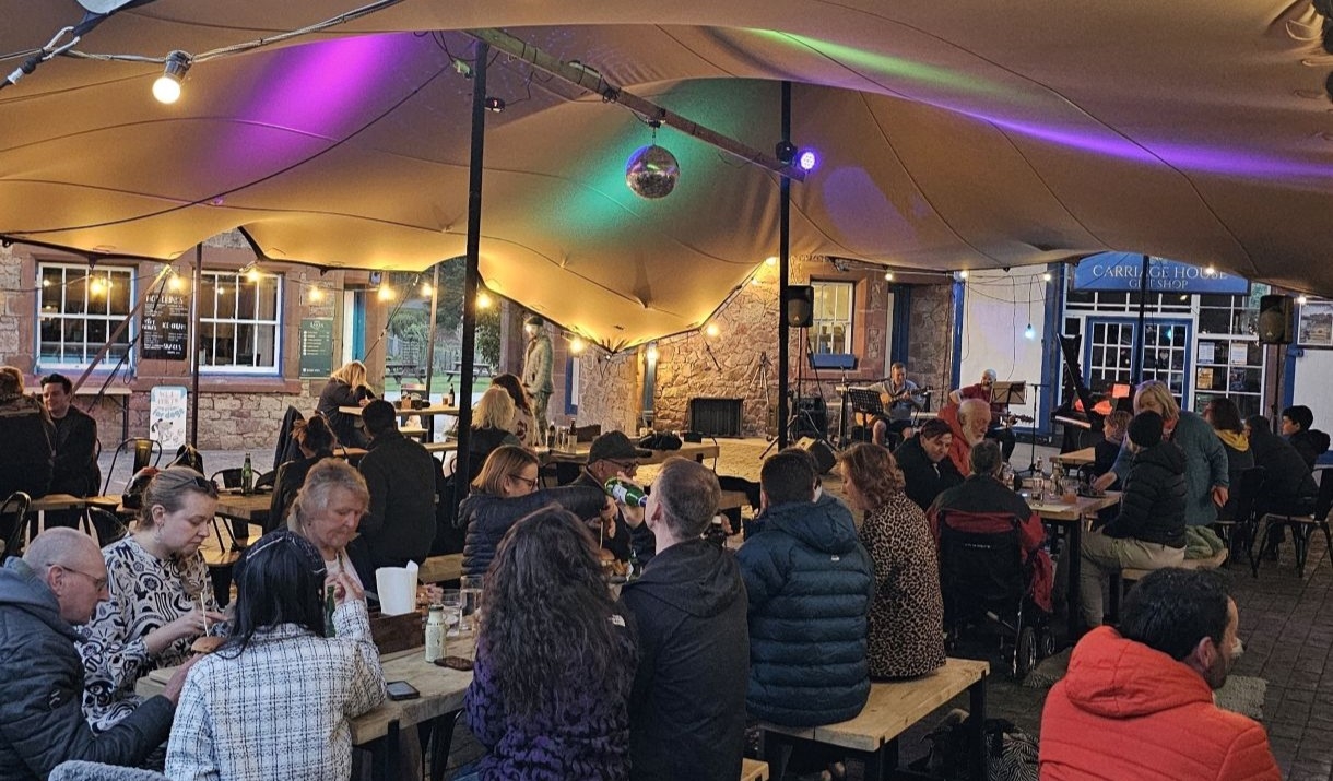 Audience enjoying the Open Mic Night in the Stable Yard at Muncaster Castle
