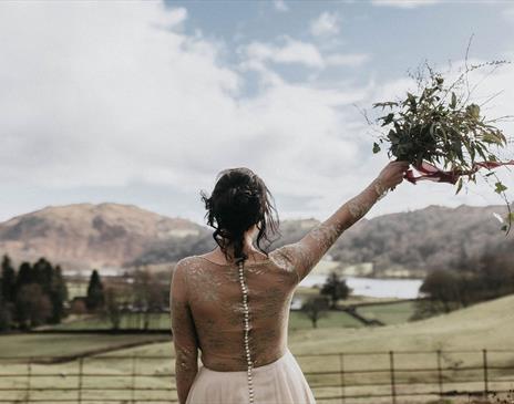 Bride with Raised Bouquet Overlooking Scenic Views from a Wedding at Allan Bank in Grasmere, Lake District