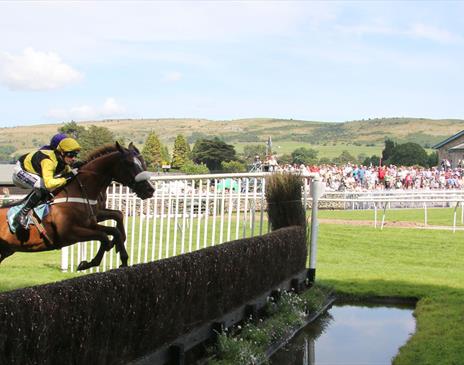 Horses Jumping at Summer Jump Horse Racing at Cartmel Racecourse in Cartmel, Cumbria