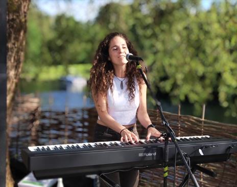 Evie Plumb playing the keyboard while singing