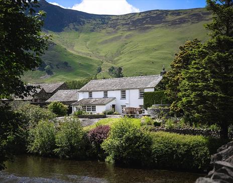 Exterior view from over the river of Grange Bridge Cottage in Borrowdale, Lake District