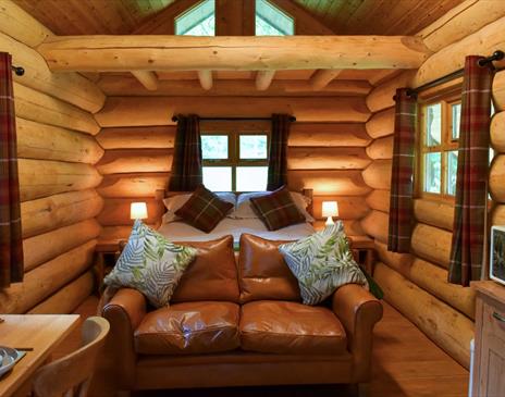 Interior of The Cabin at Grizedale Forest, with a double bed, sofa, small kitchenette, and dining table for two.