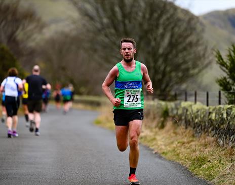 A man running along a rural road with a backdrop of mountains