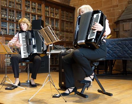 Julie Best and Jean Corrighan playing the Accordion in a library