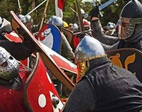 Medieval reenactment battle, two armies fighting each other with swords and shields.