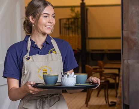 Staff serving drinks at The Stables Café at Muncaster Castle near Ravenglass, Cumbria