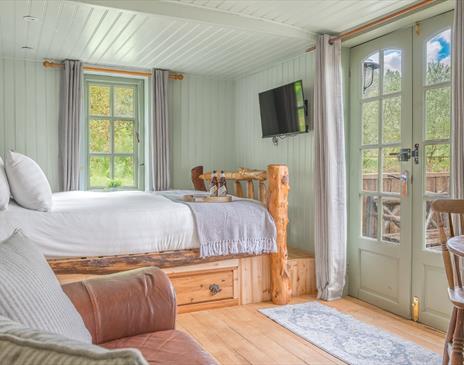 Interior of Juniper Lodge, with double bed, couch, and dining setup at Coniston Shepherd Hut Lodges in Coniston, Lake District