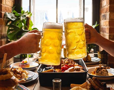 Visitors Toasting Beers over a Table with Food at Lake View Garden Bar in Bowness-on-Windermere, Lake District