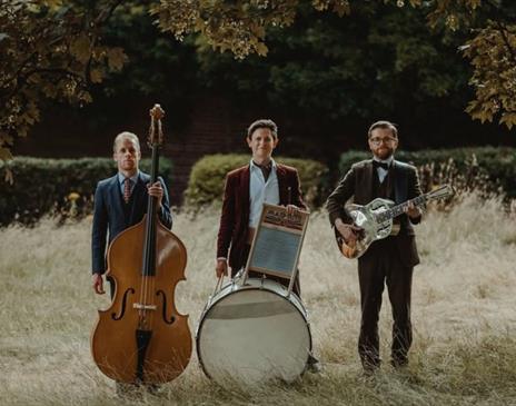 Photo of "Leeds City Stompers" standing in a field with their respective instruments