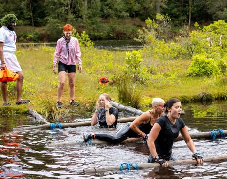 people scaling obstacles on a lake