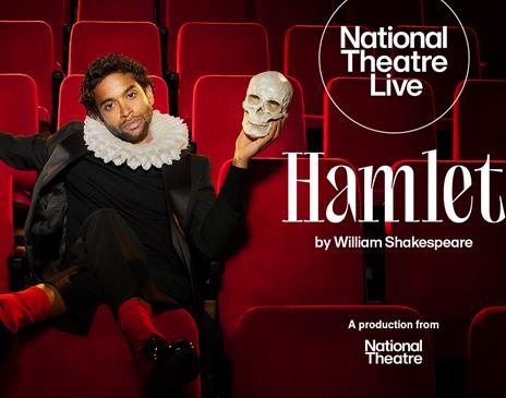 Actor Hiran Abeysekera sat in a theatre seat holding a human skull in his hand recreating a Hamlet scene