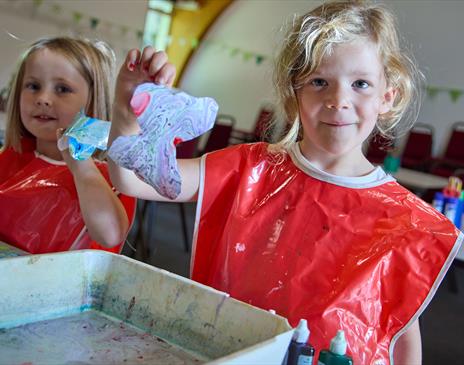 two smiling girls holding some art they have just made