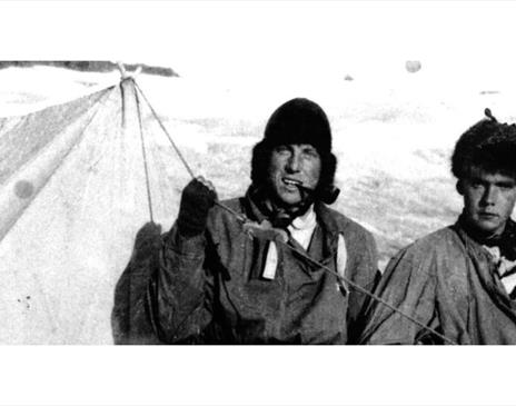 Black and white photo of Sandy Irvine and another mountaineer at a mountain campsite in the snow