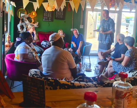 A man giving a talk to a group of people sat down on chairs