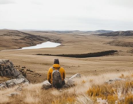A person sitting on a hill overlooking a lake in Cumbria