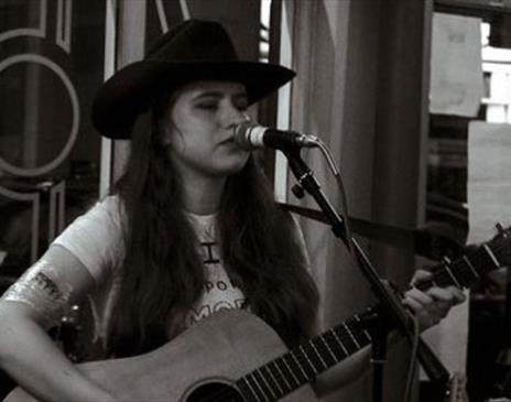 Susannah Clegg singing live while playing the guitar