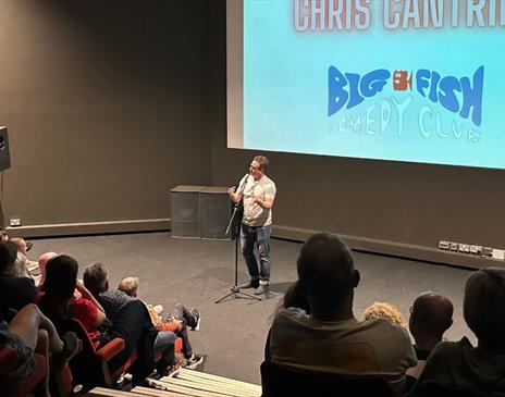 Big Fish Comedy Club live performance involving a crowd watching a male comedian on stage