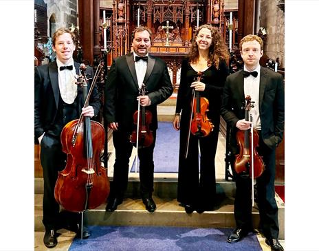 The Northern String Quartet stood in a church with their respective instruments