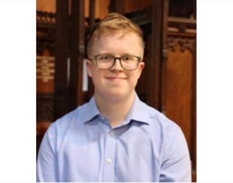 A photo of James Watson sat in front of an organ