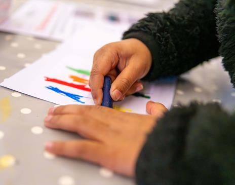 Kid drawing with a crayon on a piece of paper
