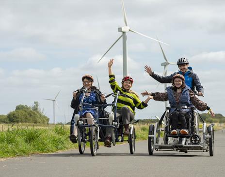 Visitors on hired cycles and accessible cycle at Watchtree Nature Reserve in Wiggonby, Cumbria