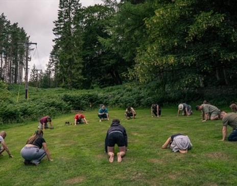 photo of people laying down in a circle in a field