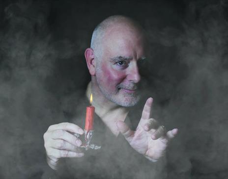 Photo of Scrooge holding a candle surrounded by mist