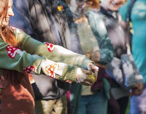 A group of people looking at a girl who is squeezing a fruit