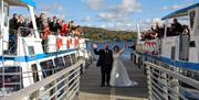 Bridal Couple and Wedding Guests on a Jetty and Windermere Lake Cruises Vessels in the Lake District, Cumbria