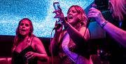 Group of Women singing passionately in a Born Noisy Karaoke Pod at BAHA in Bowness-on-Windermere, Lake District