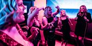 Group of Women singing passionately in a Born Noisy Karaoke Pod at BAHA in Bowness-on-Windermere, Lake District