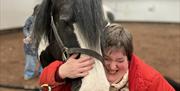 Visitor hugging a horse at Lake District Calvert Trust