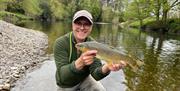 Visitor posing with fish caught on a fishing trip with West Pennine Angling Solutions in the Lake District, Cumbria
