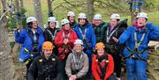 Visitors posing for a photo in ziplining gear with Lake District Calvert Trust