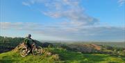 Visitor on a guided cycle tour with a scenic background with EMBR Adventures in the Lake District, Cumbria