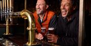 Guests drinking beer at the bar at The Swan at Grasmere in the Lake District, Cumbria