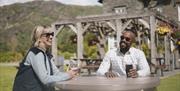 Guests sitting outside with drinks at The Coniston Inn, Coniston, Lake District
