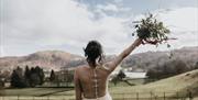 Bride with Raised Bouquet Overlooking Scenic Views from a Wedding at Allan Bank in Grasmere, Lake District