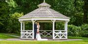 Happy Couple Posing for Wedding Photos in a Gazebo at Armathwaite Hall Hotel and Spa in Bassenthwaite, Lake District