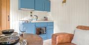 Interior of Bluebell Lodge, with kitchenette, couch, and dining setup, at Coniston Shepherd Hut Lodges in Coniston, Lake District