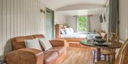 Interior of Bluebell Lodge, with double bed, couch, and dining setup, at Coniston Shepherd Hut Lodges in Coniston, Lake District
