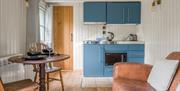 Interior of Bluebell Lodge, with kitchenette, couch, and dining setup, at Coniston Shepherd Hut Lodges in Coniston, Lake District