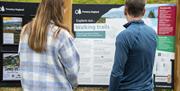 Visitors looking at walking trail maps at Whinlatter Forest in the Lake District, Cumbria