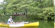 Yellow canoeist relaxes as train passes