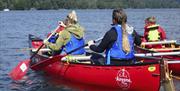 Family in rafted canoe use the steering pole to  include a mobility impaired crew member