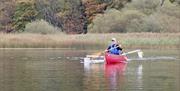 Man paddles red canoe in autumnal backdrop