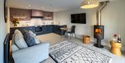 Living Area with Wood Burner and Kitchen at Hoglet Cottage in Dalston, Cumbria