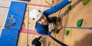 Visitor rock climbing indoors at Lake District Calvert Trust
